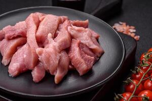 Slices of raw pork or turkey meat with salt, spices and herbs photo