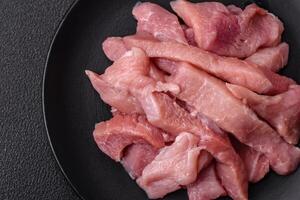 Slices of raw pork or turkey meat with salt, spices and herbs photo