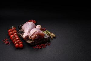 Raw chicken legs with salt, spices and herbs photo