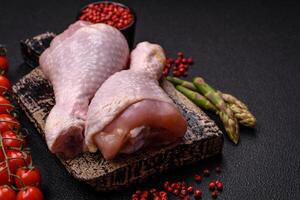 Raw chicken legs with salt, spices and herbs photo