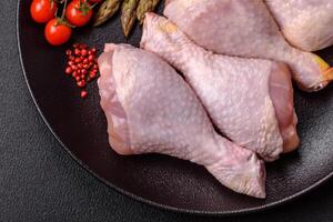 Raw chicken legs with salt, spices and herbs photo