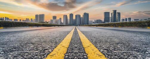 Highway road with yellow line in the middle on city skyline background at sunset photo