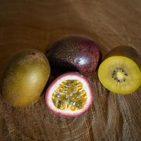 Juicy of passion fruit and kiwi on a wooden background photo