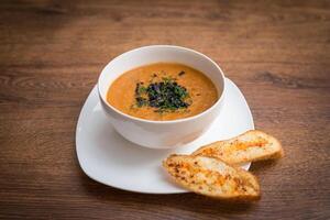 Tomato, red pepper soup, sauce with olive oil, rosemary and smoked paprika on a wooden background photo