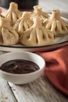 Close up to Caucasian khinkali dumplings dish served on plate. Background with ingredients and scattered spices photo