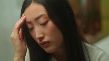 Close up face sad Asian woman girl alone lonely pensive thinking health problem upset Japanese lady suffer headache Korean Chinese female businesswoman frustrated anxious depressed emotions indoors video