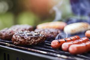 Barbecue grill sizzling with juicy burgers and hotdogs, staple of summer gatherings photo