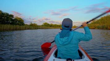 un mujer es kayak en un calma río. ella es remo con remos 4k video