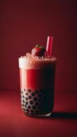 Refreshing strawberry bubble tea with tapioca pearls visible at the bottom in the glass with straw. Studio shot on the red background photo