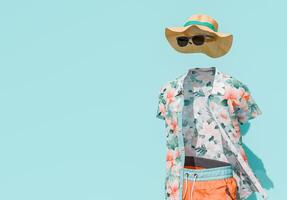Invisible Man Concept in Summer Beachwear with Floral Shirt and Straw Hat on Blue Background photo