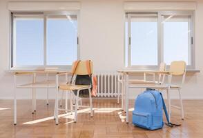 Closeup of classroom desks with backpacks and books near large windows photo