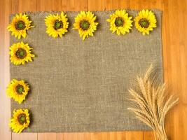 Summer yellow sunflowers organized on wooden background. Wooden space may be used for your own text or design. photo