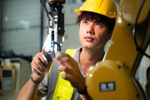 Technician who maintains a small robot arm the operation of a small robot arm used in industry is being repaired. photo