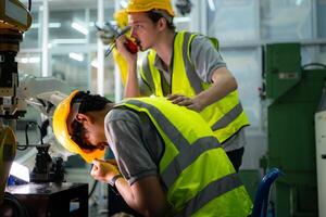 un técnico sufre un mano accidente mientras trabajando con un robot brazo en un fábrica con compañeros de trabajo Proporcionar asistencia foto