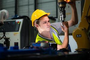 Technician who maintains a small robot arm the operation of a small robot arm used in industry is being repaired. photo