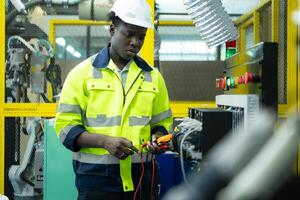 Portrait of a technician working with a digital multimeter to test the electrical system of a huge circuit board at an industrial plant using an automated hand robot. photo