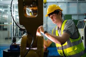 Technician who maintains a small robot arm the operation of a small robot arm used in industry is being repaired. photo