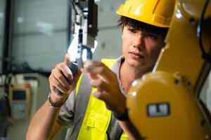 Technician who maintains a small robot arm the operation of a small robot arm used in industry is being repaired. photo