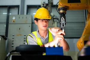 Technician who maintains a small robot arm the operation of a small robot arm used in industry is being repaired. photo