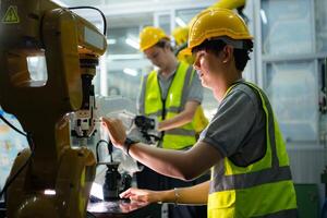 A technician suffers a hand accident while working with a robot arm in a factory with co-workers providing assistance photo