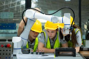 Group of engineers and technicians learning the technology to control hand robots for industrial usage. photo