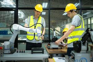 Group of engineers and technicians learning the technology to control hand robots for industrial usage. photo