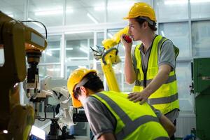 A technician suffers a hand accident while working with a robot arm in a factory with co-workers providing assistance photo