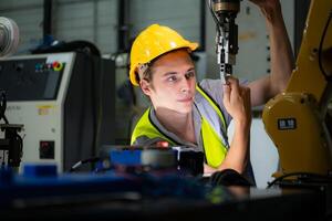 Technician who maintains a small robot arm the operation of a small robot arm used in industry is being repaired. photo