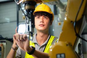 Technician who maintains a small robot arm the operation of a small robot arm used in industry is being repaired. photo