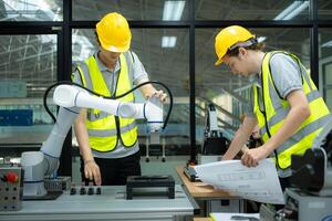 Group of engineers and technicians learning the technology to control hand robots for industrial usage. photo