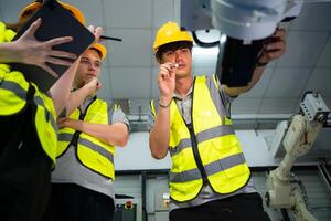 Engineer and technician discussing the robotic arm in factory about work operating, maintenance and repair photo