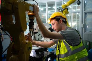 Technician who maintains a small robot arm the operation of a small robot arm used in industry is being repaired. photo