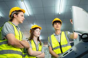 Both of young factory worker wearing a hard hat looking at a computer screen used to control production. photo