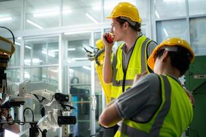 A technician suffers a hand accident while working with a robot arm in a factory with co-workers providing assistance photo