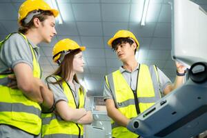 Both of young factory worker wearing a hard hat looking at a computer screen used to control production. photo