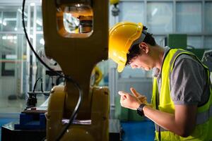 A technician suffers a hand accident while working with a robot arm in a factory with co-workers providing assistance photo