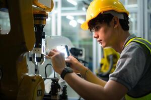 Technician who maintains a small robot arm the operation of a small robot arm used in industry is being repaired. photo