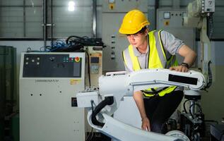 Technician who maintains a small robot arm the operation of a small robot arm used in industry is being repaired. photo