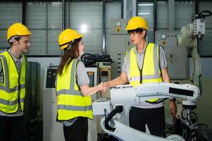 Engineer and worker shaking hands while working on industrial machine in factory photo