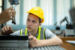 retrato de un técnico joven masculino trabajador en un fábrica trabajando en un pequeño robot máquina foto