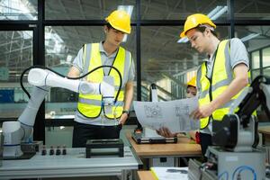 Group of engineers and technicians learning the technology to control hand robots for industrial usage. photo