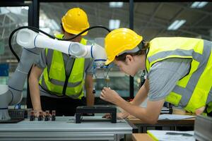 Group of engineers and technicians learning the technology to control hand robots for industrial usage. photo