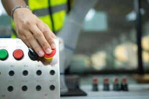 de cerca de mano prensado el detener botón en el controlar panel de un industrial máquina. foto