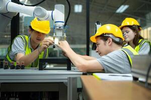 Group of engineers and technicians learning the technology to control hand robots for industrial usage. photo