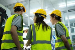 Back view of group young factory worker wearing a hard hat looking at a computer screen used to control production. photo