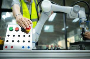 Close-up of hand pressing the stop button on the control panel of an industrial machine. photo