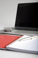 Phone, laptop and empty notebook on the desk photo