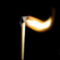 Wooden match burning on a black background photo