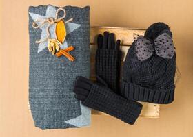 Set of winter cap, scarf and gloves on colored background photo