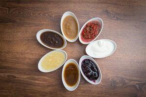 Sauces and spices. A set of popular sauces and spices on a wooden background. photo